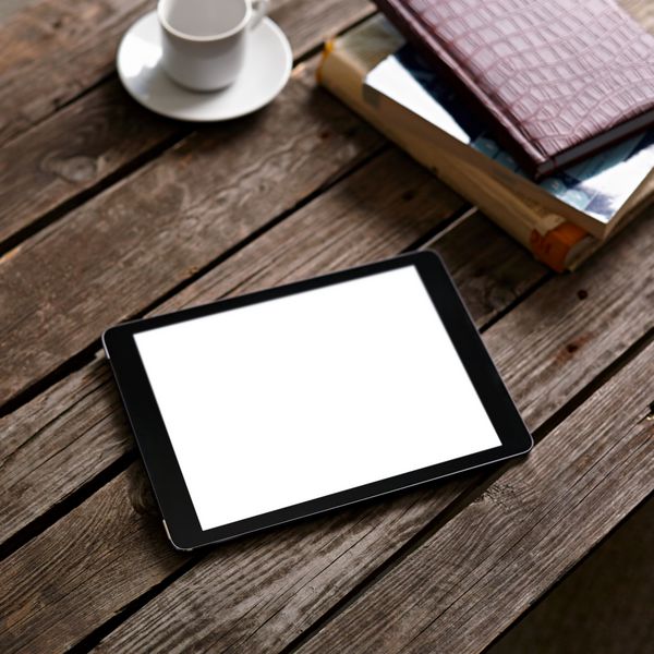 رایانه لوحی دیجیتال با صفحه نمایش جدا شده روی میز چوبی با فنجان قهوه