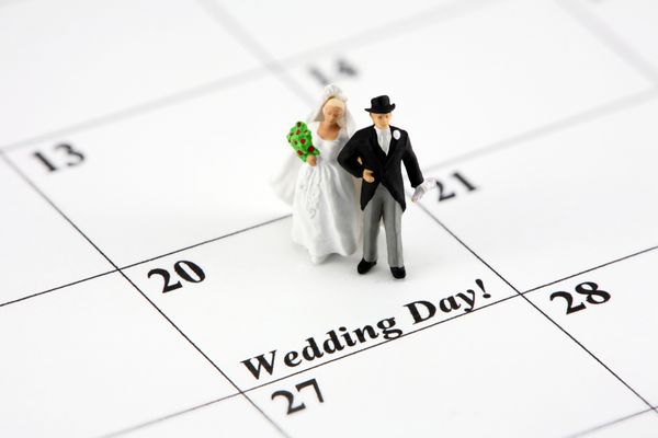 عروس و داماد مینیاتوری در تقویمی که روی آن نوشته شده است روز عروسی