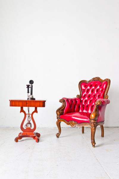 صندلی راحتی لوکس قدیمی و تلفن در اتاق سفید