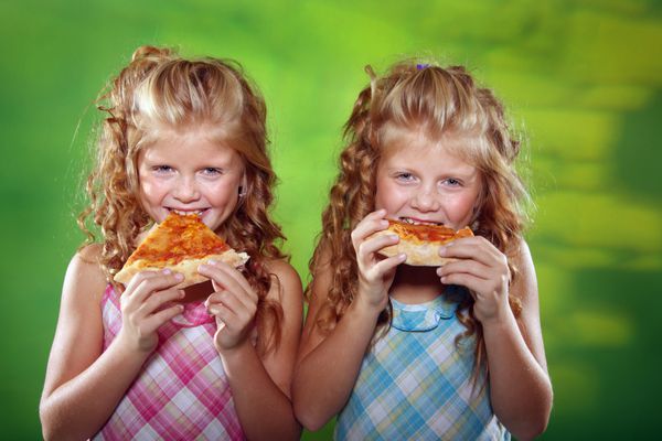 دو دختر در حال خوردن پیتزا در زمینه سبز