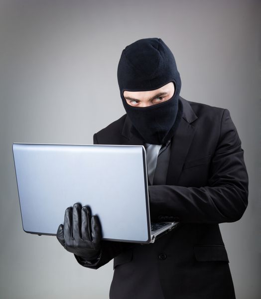 هکر رایانه ای با کت و شلوار و کراوات داده ها را از رایانه لپ تاپ می دزدد