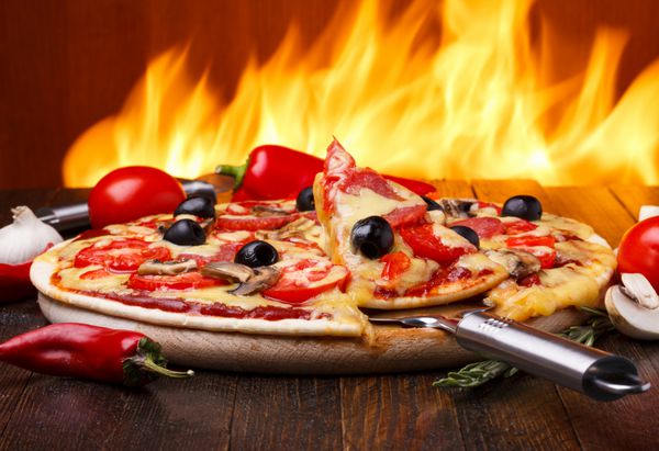پیتزا داغ با آتش فر در پس زمینه