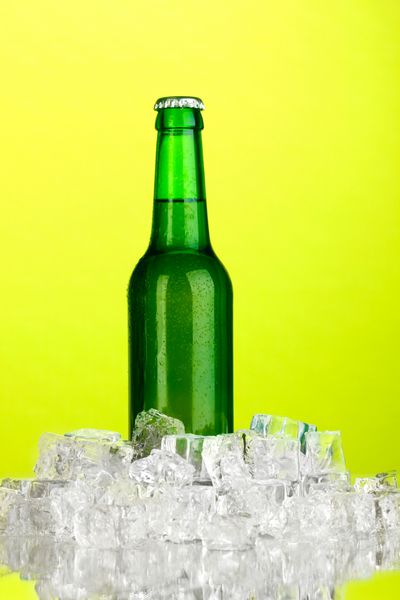 بطری آبجو در یخ در پس زمینه سبز