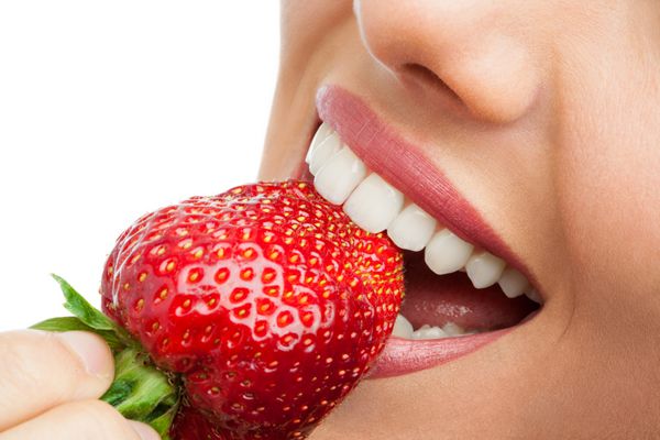 نمای نزدیک از دندان هایی که توت فرنگی را می جوند