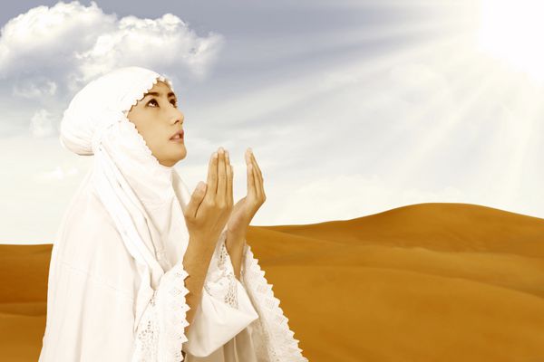 زن مسلمان آسیایی سفیدپوش در حال نماز در صحرا