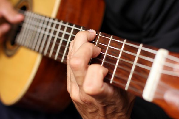 نزدیک گیتار آکوستیک در دستان نوازنده