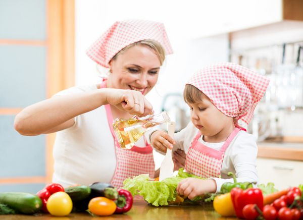 زن و کودک خوشحال در حال آماده کردن غذای سالم با هم