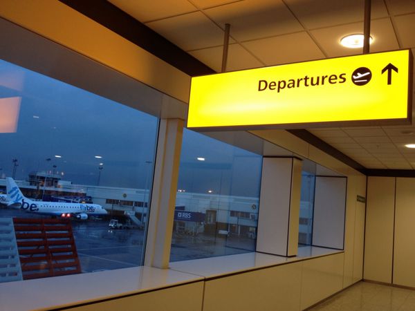 تابلوی خروج در فرودگاه با هواپیما در پس زمینه