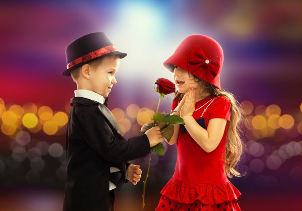 پسر کوچک دوست داشتنی که یک گل رز به دختر هدیه می دهد