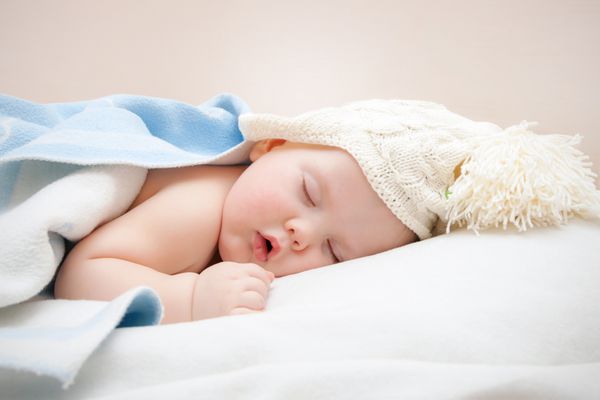 کودک خواب ناز در کلاه بافتنی با پومپوم