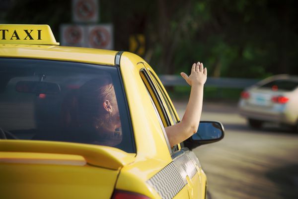 زنی در تاکسی که دستش را از پنجره ماشین بیرون می‌کشد