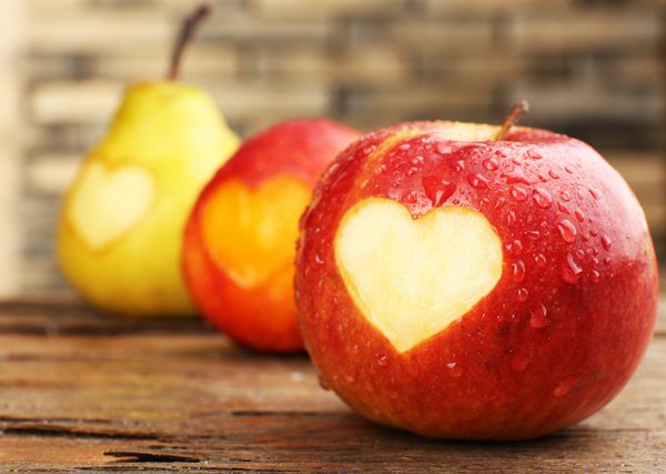 میوه های رسیده با قلب روی میز چوبی نمای نزدیک