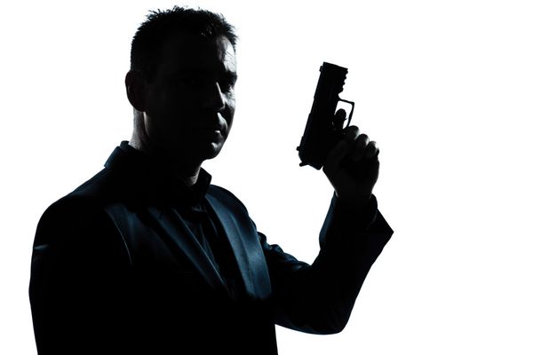 یک مرد کارآگاه پلیس جنایی جاسوس قفقازی که تصویر پرتره اسلحه در دست دارد در پس زمینه سفید جدا شده در استودیو