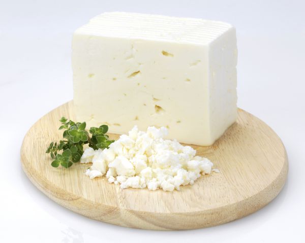 یک پنیر سنتی یونانی سفید به نام فتا و پونه کوهی روی یک بشقاب چوبی