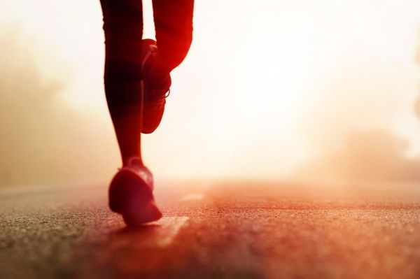 دونده پاهای ورزشکار در حال دویدن در جاده مفهوم تناسب اندام زن طلوع آفتاب آهسته دویدن تمرین تندرستی