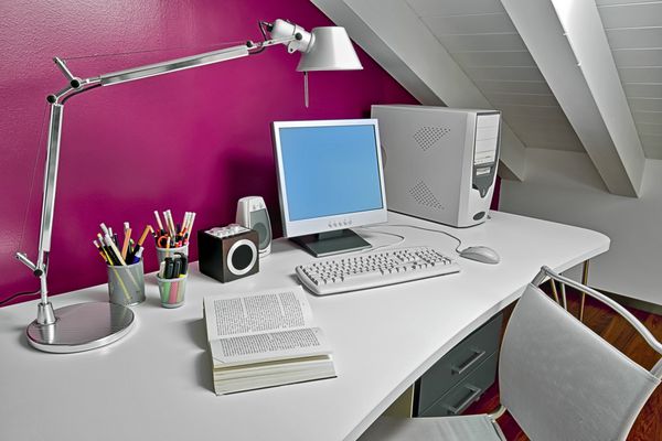 میز مدرن در اتاق زیر شیروانی با کامپیوتر و کتاب باز شده است