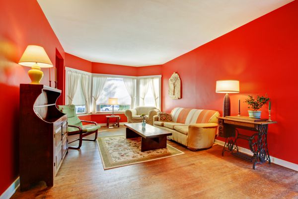 اتاق نشیمن قرمز بزرگ با چوب سخت و مبلمان عتیقه با لامپ