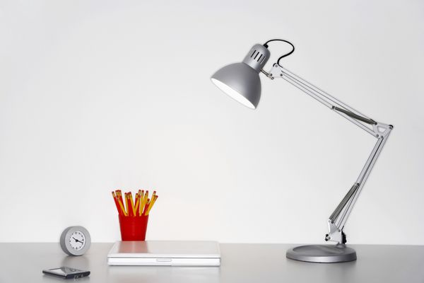 لامپ زاویه دار لپ تاپ ساعت جا مداد و تلفن همراه روی میز