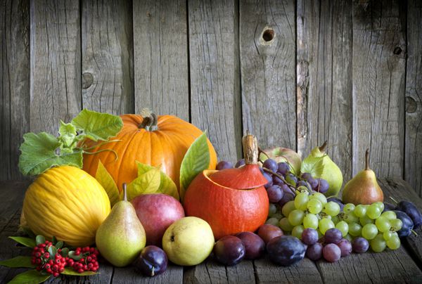 سبزیجات کدو تنبل و میوه ها در فصل پاییز هالووین طبیعت بی جان روی تخته های چوبی قدیمی