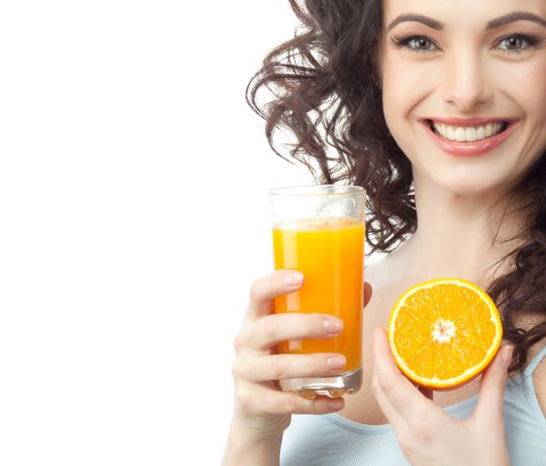 پرتره سر و شانه زن جذاب قفقازی خندان جدا شده روی استودیو سفید پوست در حال نوشیدن آب پرتقال