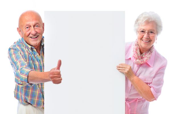 زوج مسن خندان شاد که تخته ای خالی جدا شده روی سفید در دست دارند