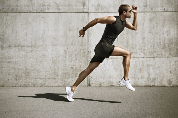 مرد ورزشکار شروع به دویدن مرد جوان در حال دویدن دیوار سیمانی جلو