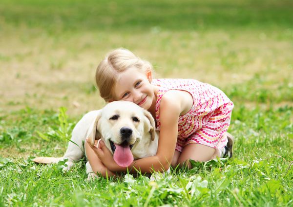 یک دختر بچه با سگ خانگی اش در فضای باز در پارک