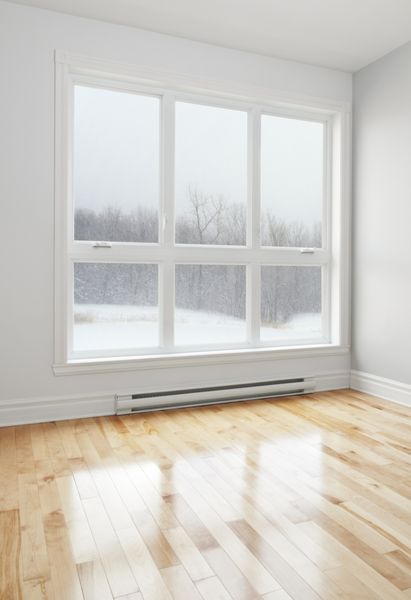 منظره زمستانی از پنجره بزرگ یک اتاق خالی دیده می شود