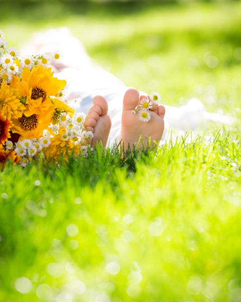 پای کودکان با گل بهاری روی چمن سبز