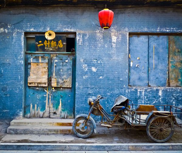 گاری موتوری پارک شده در مقابل نمای آبی در حال پوسیدگی یک مغازه متروکه در پینگ یائو چین