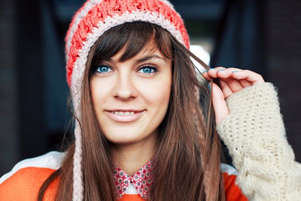 پرتره دختر جوان خندان و بامزه در هوای سرد با لباس های رنگی و کلاه گرم زن جوان شاد در حال تفریح در فضای باز