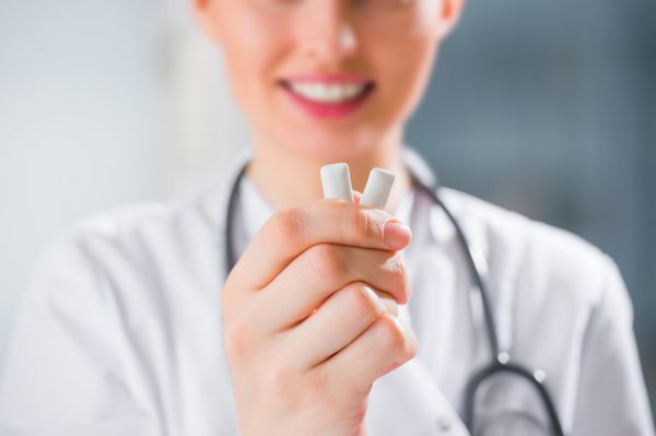 پزشک زن - دندانپزشک - در حال نشان دادن آدامس مفهوم مراقبت از دندان
