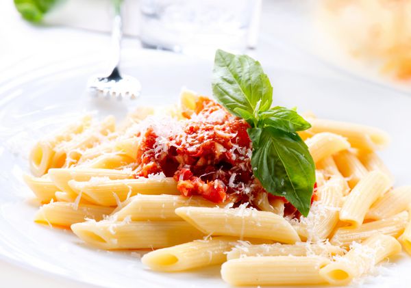 پاستا پاستا پنه با سس بولونیز پنیر پارمزان و ریحان روی چنگال غذاهای ایتالیایی غذای مدیترانه ای