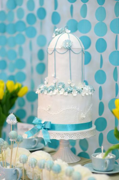 کیک عروسی دو طبقه تزئین شده با گل های آبی