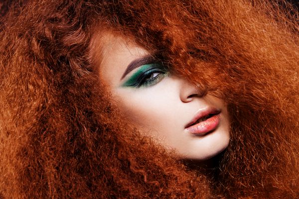 مدل زیبا با موهای شاداب مجعد قرمز و آرایش چشم سبز روشن