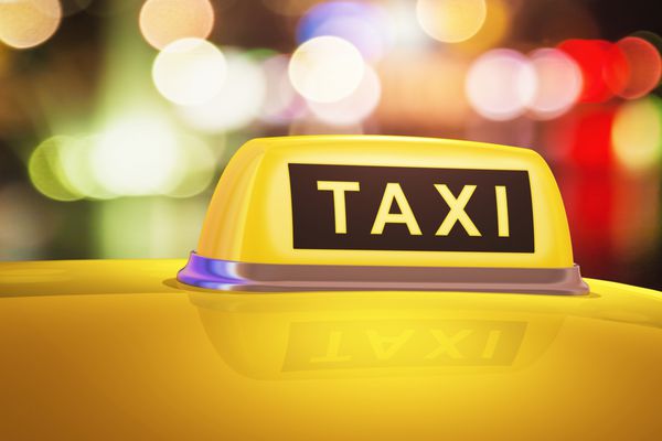 نمای ماکرو تابلو زرد تاکسی روی ماشین در خیابان شهر عصر یا شب در فضای باز