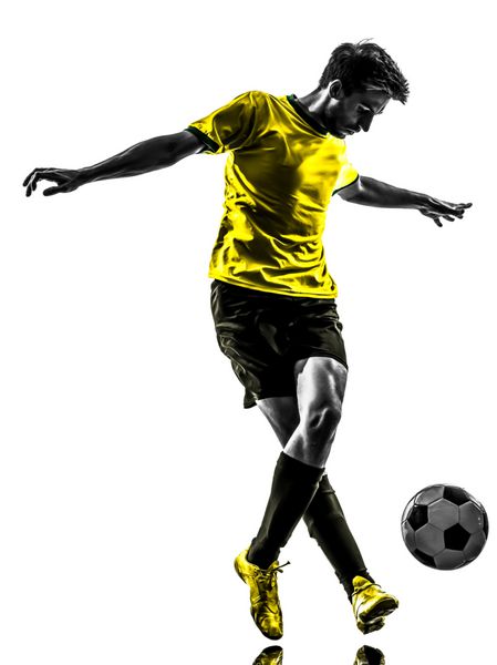 یک مرد جوان فوتبالیست برزیلی در حال دریبل زدن در استودیو silhouette جدا شده روی پس زمینه سفید