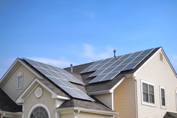 پنل های خورشیدی پوولتائیک کارآمد صرفه جویی در انرژی سبز تجدید پذیر بر روی سقف خانه های حومه ای چند شیروانی بر فراز آسمان آبی