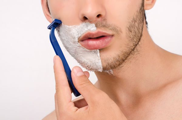 تراشیدن ریش با تیغ مرد جوانی که صبح ریش خود را با تیغ تراشیده است