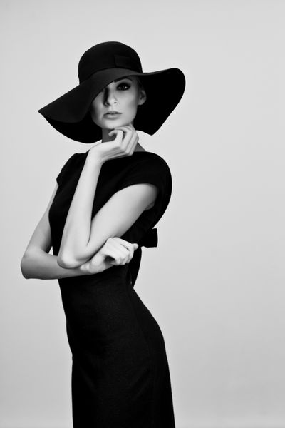 پرتره مد بالا از زن ظریف با کلاه و لباس سیاه و سفید استودیو اس