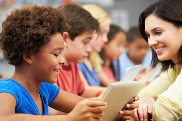 دانش آموزان در کلاس با استفاده از تبلت دیجیتال با معلم