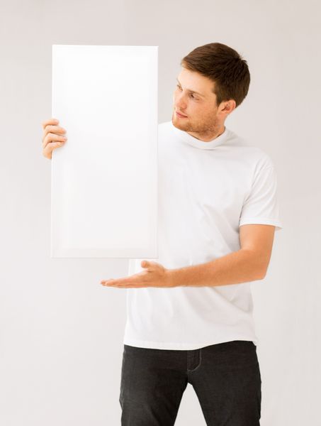 تصویر مرد جوانی که تخته سفید سفید را در دست گرفته است