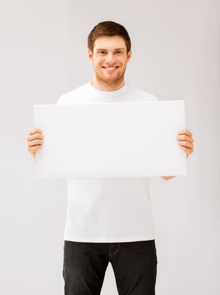 تصویر مرد جوانی که تخته سفید سفید را در دست گرفته است