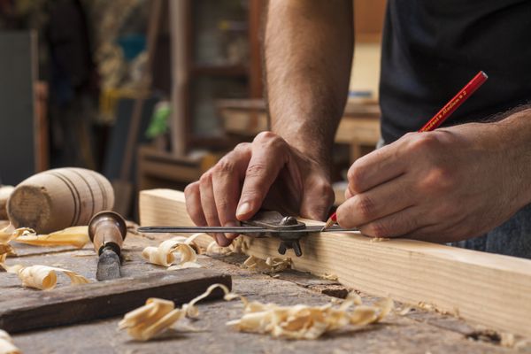 دست یک نجار که یک تخته چوبی را اندازه می گیرد