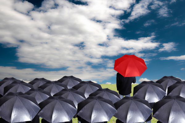 رهبر در دست گرفتن چتر قرمز برای نمایش متفاوت فکر کنید با آسمان آبی