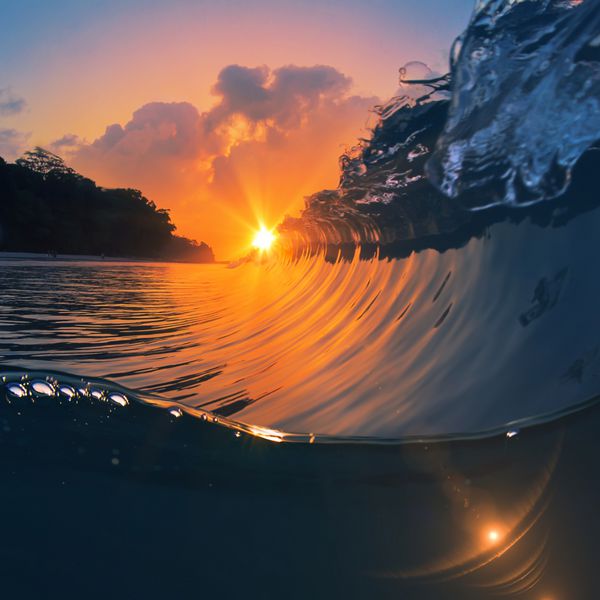 موج موج سواری کامل در حال شکستن اقیانوس در زمان غروب آفتاب و قسمت پایین زیر آب به عنوان الگوی طراحی با پرتوهای خورشید