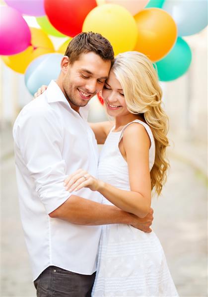 تعطیلات تابستانی جشن و مفهوم عروسی - زوج با بادکنک های رنگارنگ و حلقه نامزدی