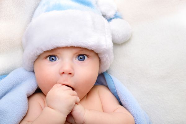 پسر بچه ناز کریسمس نوزاد زیبا با کلاه بابا نوئل و چهارخانه نرم آبی با بیان مثبت واضح