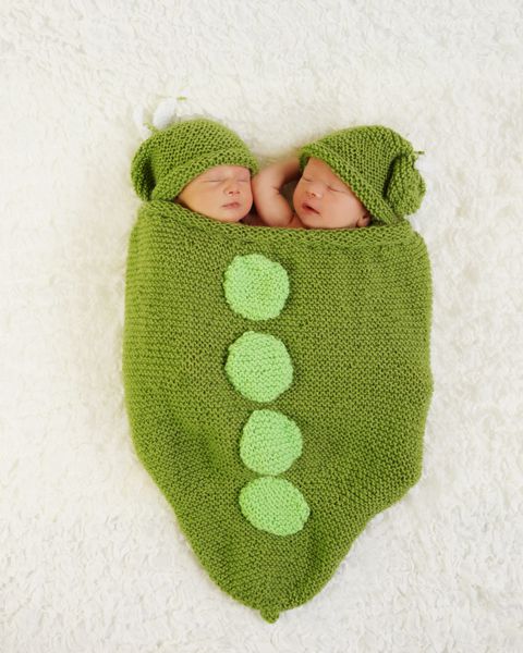 خواب دوقلوهای نوزاد تازه متولد شده داخل پادری بافتنی با کلاه نخودی
