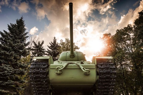 تانک سنگین kv-85 شوروی از جنگ جهانی دوم با جنگل و آسمان دراماتیک در پس زمینه بنای یادبود در سنت پترزبورگ
